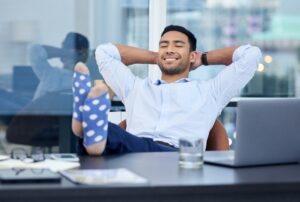 Basking in glory. Shot of a very satisfied businessman relaxing at his desk at work.