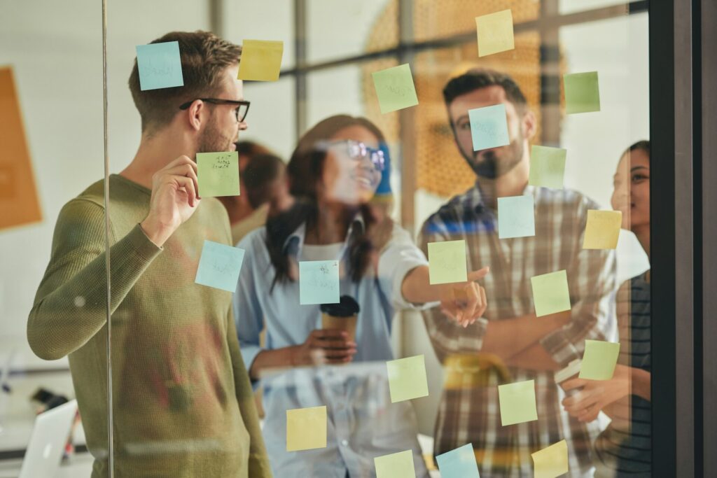 Smart and talented young people putting sticky notes on wall